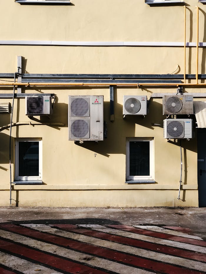Services Yellow building facade with multiple air conditioning units mounted on wall.